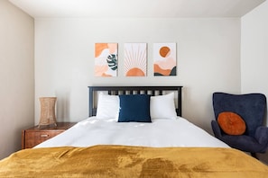 The primary bedroom is equipped with a queen bed and mattress that everyone seems to love. The midcentury nightstand offers a little extra space for storage and the butterfly chair is a comfy nice touch for a great book!