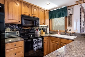 Kitchen with dishwasher, stocked with dishes, utensils, pots & pans, linens, etc