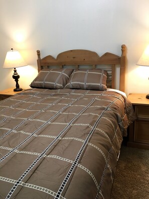 The brown bedroom has a queen bed, side tables, and dresser.