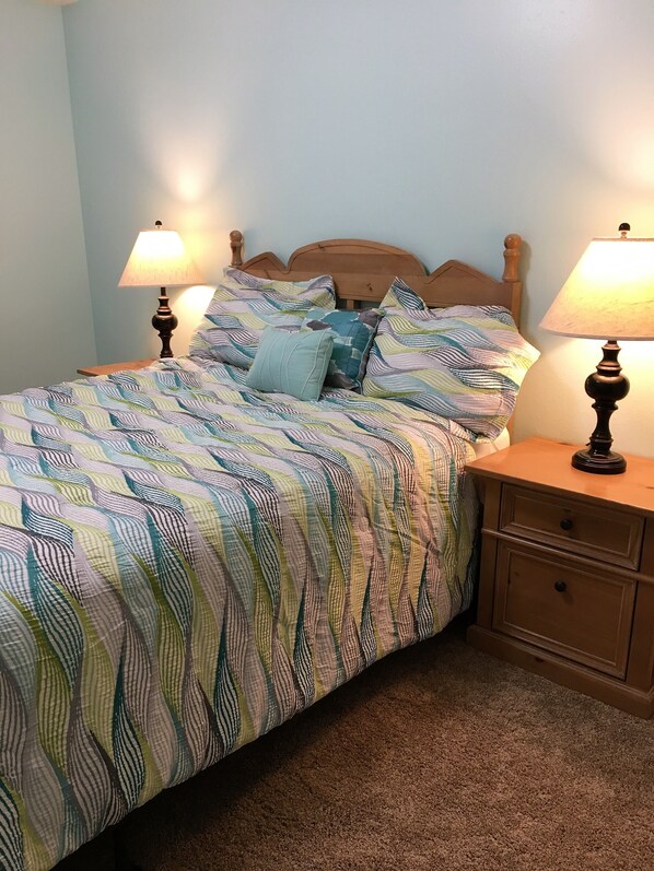 The blue bedroom has a queen bed, two side tables, a dresser and a small desk.