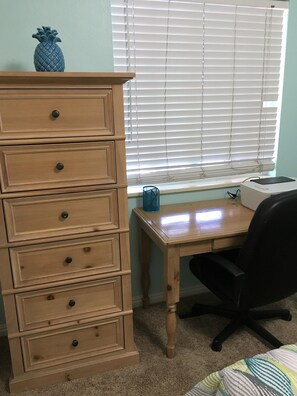 There is a small desk in the blue bedroom.  