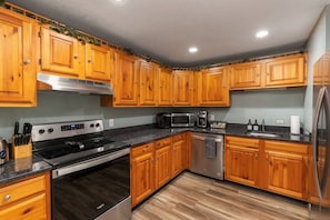 Fully stocked kitchen with granite countertops and stainless-steel appliances. Water and ice machine on fridge.