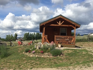 The Wolf Den cabin in the spring with it's garden and firepit showing