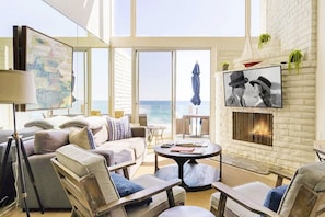 Living room has comfortable seating, 55" smart TV, fireplace and oceanfront view