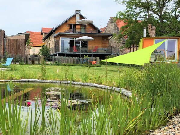 Gartenansicht mit Schwimmteich und finnischer Sauna