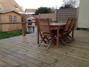 La terrasse au nord avec table et chaises pour 8 personnes, jardin et barbecue