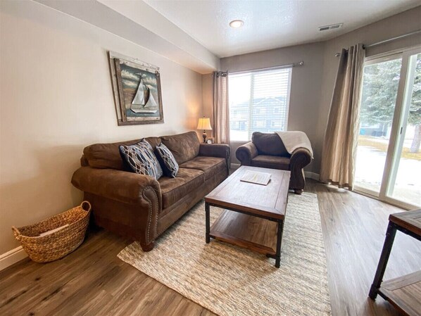 Warm and welcoming living room with natural light, plush seating, and a peaceful view outside.