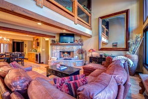 Great room with stone fireplace, flat screen TV, and vaulted ceiling