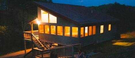 Overlook at night with the screeened porch and fire pit aglow