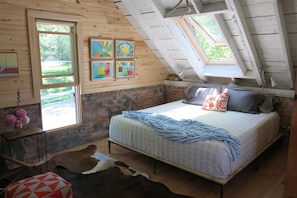 A king size tempurpedic bed lies beneath an operable skylight.
