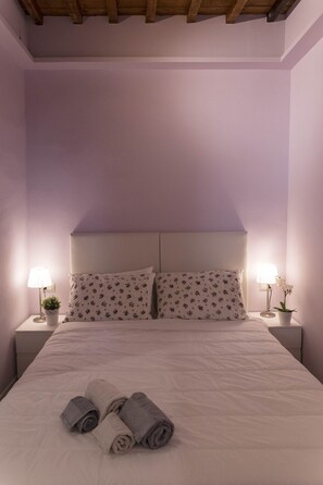 The bedroom features exposed beam ceiling and nightstands with table lights.