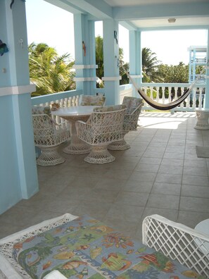 Veranda has chairs, table, and a hammock.