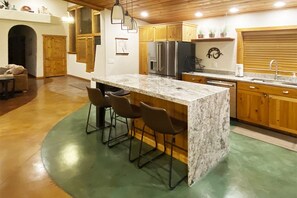 Gourmet kitchen w/ waterfall island, large fridge and equipped w/ necessities