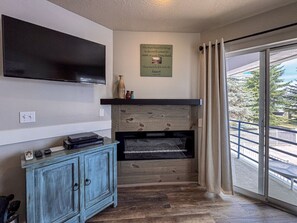 Cozy corner with fireplace, TV, and deck access—perfect for relaxing or entertaining.