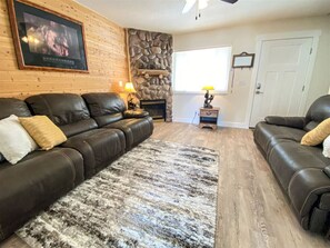 Cozy Living Room with cobblestone gas fireplace and leather couches to sit and enjoy time with family or friends.