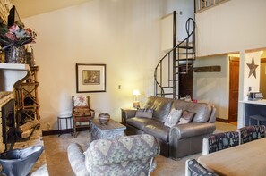 Large sofa with spiral staircase to the loft.  Hallway in the back right corner.