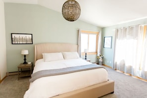 The upstairs master bedroom boasts a king-sized bed with plush bedding, an ensuite bathroom, and epic views of the surrounding mountains. It's a luxurious escape offering tranquility and comfort.