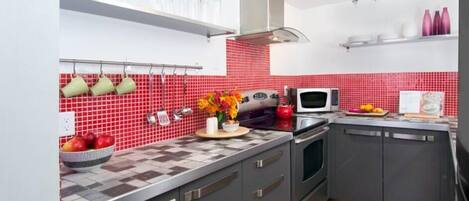 Newly-renovated kitchen with easy touch close cabinets and a vibrant red tile back splash