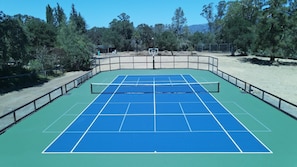 Tennis court with 2 pickleball courts and basketball hoop.
