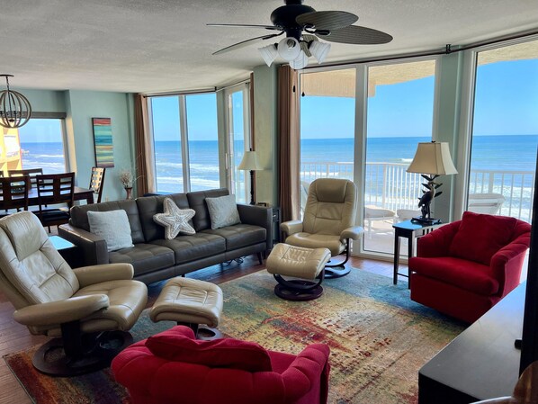 Open living, dining, kitchen with floor to ceiling windows on oceanfront side.