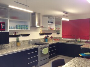 A fully equipped granite gourmet counter kitchen with modern led chandeliers.
