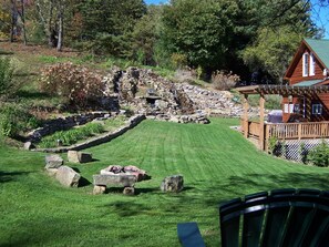 View of 34 ft waterfall and fire pit, back deck, gas grill and outdoor furniture