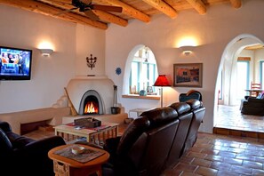 Living room large flat screen satellite TV & wood burning kiva fireplace