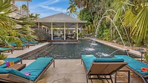 The spacious patio surrounding the pool is paved in Travertine, with chaise lounges...