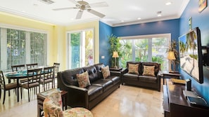The living area has bright, tropical colors, tall ceilings, and luxurious modern furnishings...