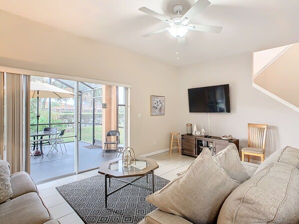 Cozy living room with a flat-screen TV and natural light, opening to a relaxing patio.