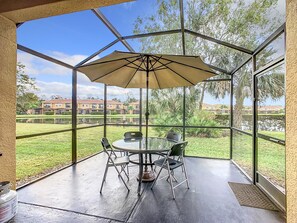 Scenic screened patio with outdoor seating and lush greenery views.