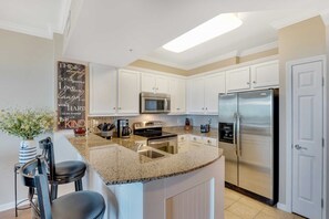 Fully equipped kitchen with stainless steel appliances, granite counters and peninsula bar with seating for 2