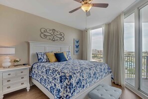 Master bedroom with king bed, ceiling fan, nightstand and lamp, private access to balcony and views over resort