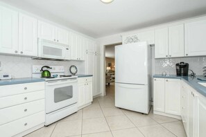 Well appointed kitchen with solid surface counters, raised panel cabinetry, and diagonal tile work throughout.