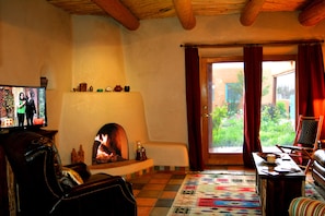 Living room with flat screen satellite TV & traditonal southwest wood burning kiva fireplace