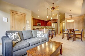 View of the main entrance behind the couch, and entryway in back leading towards bedroom area