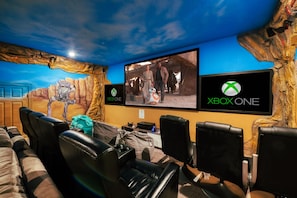 Themed games room has a large projection screen, theater seats and gaming chairs