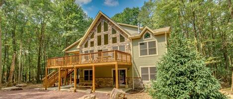 Angled photo of the exterior of this luxurious Poconos vacation rental, with view of elevated porch.