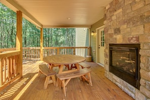 The outdoor fireplace located on the porch, next to a round picnic table.