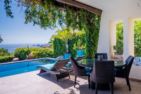 Poolside patio with shady seating area and ocean views