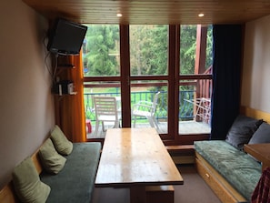 View towards the balcony showing tables, sofas and TV screen in left hand corner