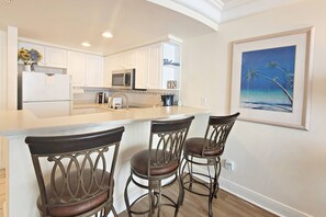 Kitchen overlooks living area and features a eat-at bar that sits three.