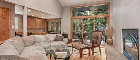 Relaxing living room with gas fireplace, desk, extra window seating for two and access to deck.