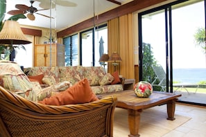 Living Room - Beautifully furnished and appointed oceanfront living room that opens onto the grassy lawn. Enjoy the birds playing and singing in the beautiful LauHala tree just outside the patio.
