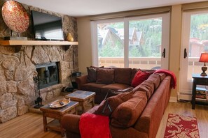 Open living area features wood burning fireplace and mountain views.