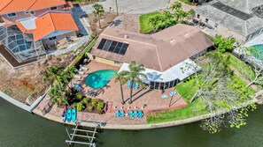 Aerial View of the private back yard.  Paver patio, bank of chaise lounges for "sunning".  Direct canal access for your enjoyment be it kayaking, fishing or whatever your desires.