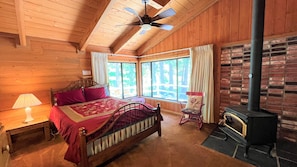 Bedroom with a queen-sized bed, wood-burning stove, and views of - Bedroom with a queen-sized bed, wood-burning stove, and views of Strawberry Creek.