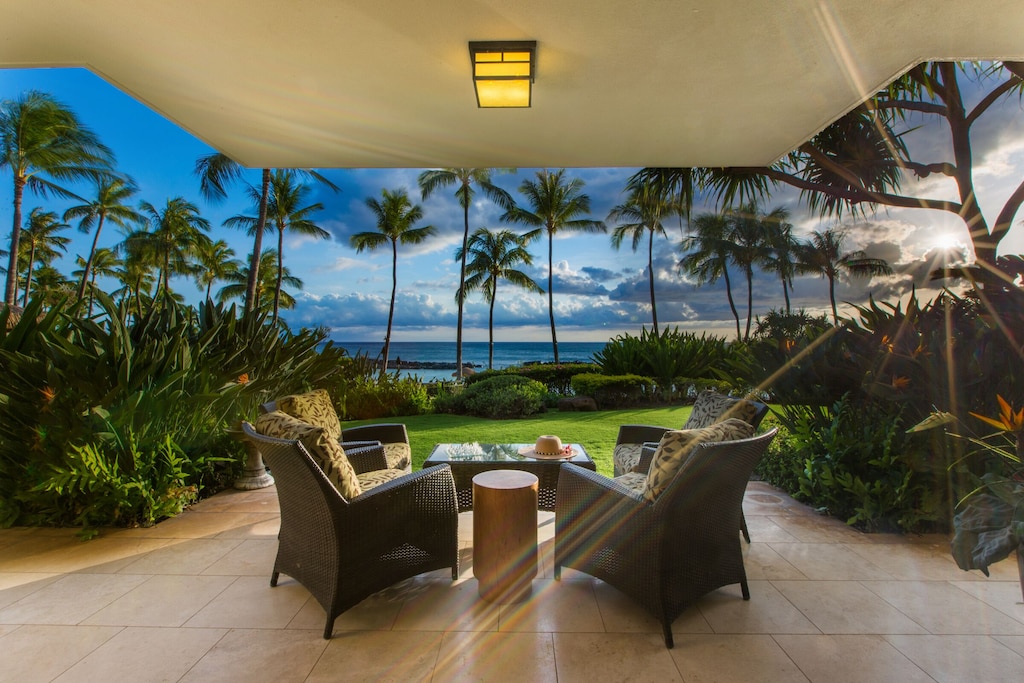 Tropical decor and ocean views from a spacious lanai equipped with chairs and a table in Oahu