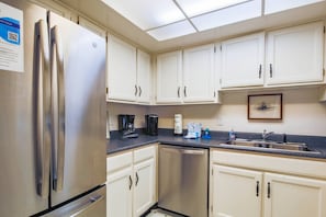 The kitchen features white cabinetry and stainless steel appliances.