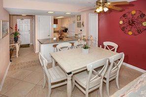 Dining area with seating for six at the table and two stools at the breakfast bar.